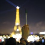 A person holds a pen, symbolising freedom of speech, as lights on the Eiffel Tower start to dim before switching off for five minutes in Paris