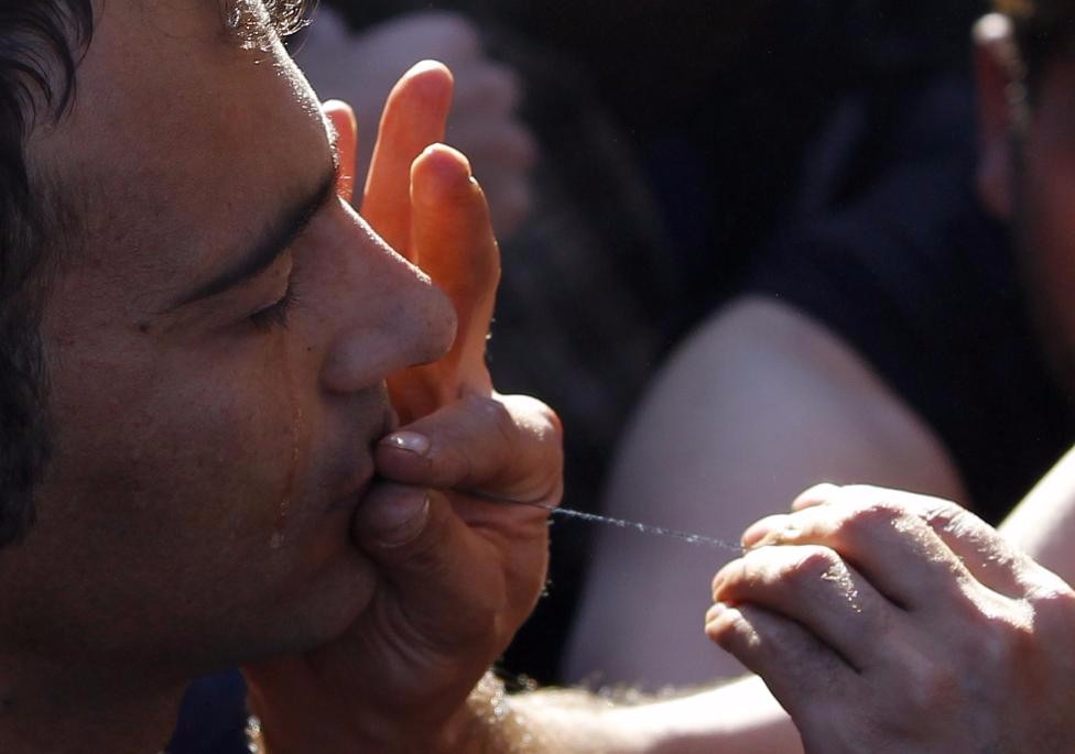 A migrant gets his mouth sewed up during a protest as he waits with others to cross the border from Greece to Gevgelija, Macedonia November 23, 2015. REUTERS/Ognen Teofilovski