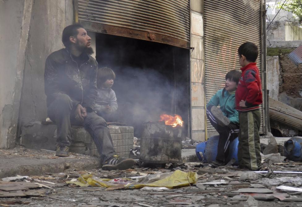 A man and children sit around a fire in the besieged area of Homs, January 30, 2014. REUTERS/Thaer Al Khalidiya